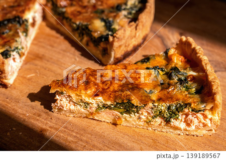 Traditional Lorraine quiche made from shortcrust pastry with an egg-and-cream filling and red fish, close-up of a slice of quiche on a wooden oak board, delicious homemade pastries Traditional Lorraine quiche made from shortcrust pastry with an egg-and-cream filling and red fish, close-up of a slice of quiche on a wooden oak board, delicious homemade pastries 139189567