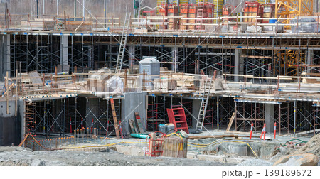 Active construction site with scaffolding, ladders, and concrete formwork Active construction site with scaffolding, ladders, and concrete formwork 139189672