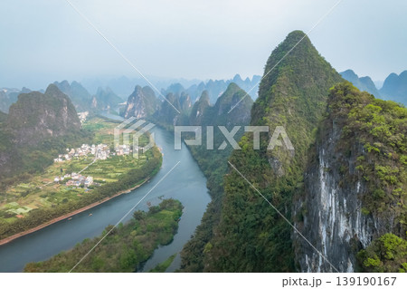 Lush karst peaks rise steeply from calm river waters. China. Lush karst peaks rise steeply from calm river waters. China. 139190167