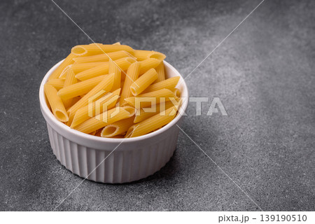 Italian uncooked dry penne regate pasta ready for cooking. Dry penne pasta Italian uncooked dry penne regate pasta ready for cooking. Dry penne pasta 139190510