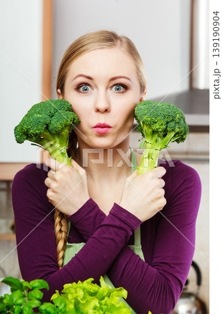 Woman in kitchen with green fresh broccoli Woman in kitchen with green fresh broccoli 139190904