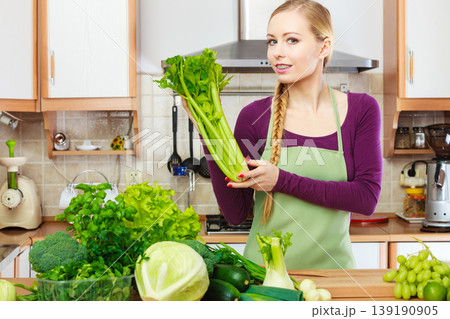 Woman in kitchen with green vegetables Woman in kitchen with green vegetables 139190905