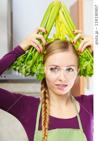 Woman in kitchen holds green celery 139190907