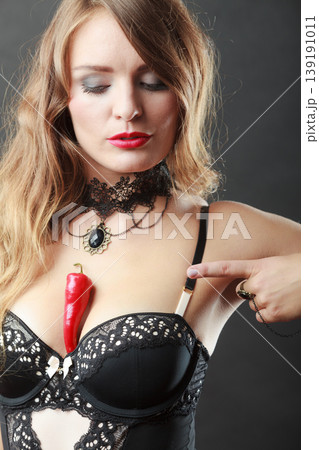 Woman wearing sexy lingerie holding chilli on chest Woman wearing sexy lingerie holding chilli on chest 139191011