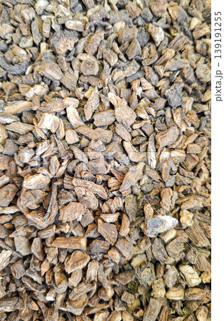 Dried burdock root lies spread out on a flat surface. The rough texture is visible, highlighting its natural form. This root often features in herbal remedies and natural medicine. Dried burdock root lies spread out on a flat surface. The rough texture is visible, highlighting its natural form. This root often features in herbal remedies and natural medicine. 139191255