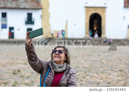 Happy senior woman concept. Senior travel concept. Senior woman taking selfies at the beautiful colonial town of Villa de Leyva in Colombia 139191443