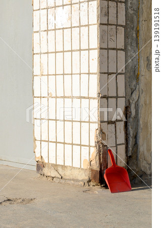 red plastic dustpan for trash lies in the corner by a wall faced with white square tiles red plastic dustpan for trash lies in the corner by a wall faced with white square tiles 139191518