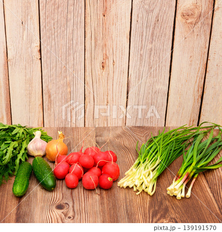 set of cucumbers, radishes, garlic, onions and green feathers against a wooden fence background set of cucumbers, radishes, garlic, onions and green feathers against a wooden fence background 139191570