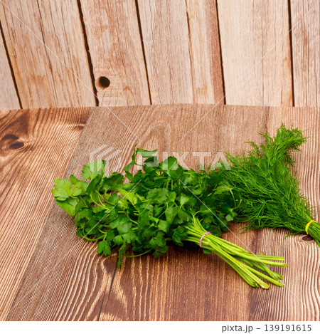 two bunches of fresh green parsley and dill on a wooden table 139191615