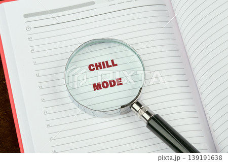 A magnifying glass rests on an open daily planner. The phrase Chill Mode appears magnified in red text on the lined page, indicating a focus on relaxation 139191638