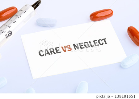 A white card with CARE VS NEGLECT message lies on a white surface, bordered by a syringe, bright orange capsules, and pale blue tablets 139191651