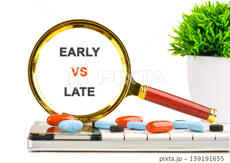 A magnifying glass displays EARLY VS LATE above blue and orange pills resting on a white keyboard, next to a green plant A magnifying glass displays EARLY VS LATE above blue and orange pills resting on a white keyboard, next to a green plant 139191655