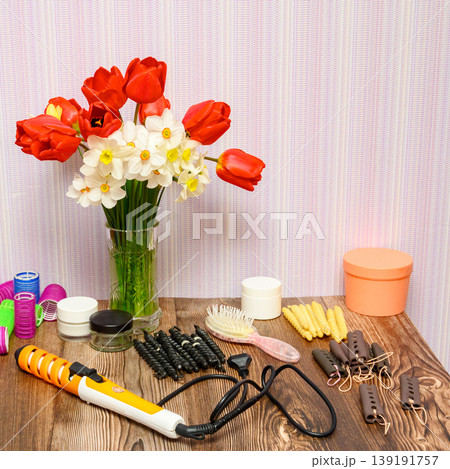still life with spring flowers in a vase and hairdressing styling tools on a wooden table 139191757