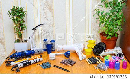 large set of hair styling tools with indoor plants and a desk lamp on a wooden surface 139191758