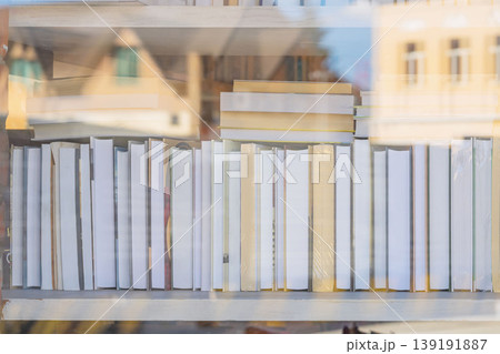 Books on shelf seen through window with city reflections, showing bookstore display, library. Concept of books, literature, study, knowledge, learning, reading theme, blurred background Books on shelf seen through window with city reflections, showing bookstore display, library. Concept of books, literature, study, knowledge, learning, reading theme, blurred background 139191887