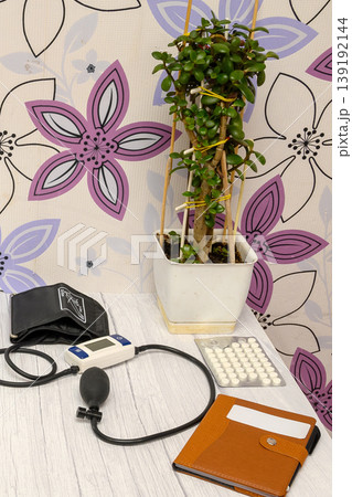 tonometer and pills on the table near a houseplant tonometer and pills on the table near a houseplant 139192144