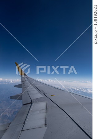 ravel by Airplane Window with Sky and Clouds. Airplane Wing View with Blue Sky and Clouds. 139192621