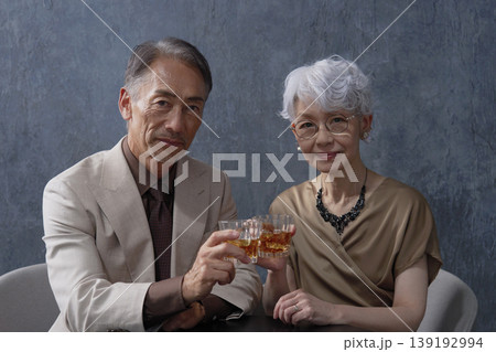 ウィスキーを飲むシニアの夫婦　黒背景　ポートレート　カメラ目線 139192994