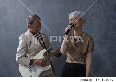 シニアのミュージシャン　男性のギタリストと女性のボーカル　黒背景 139193015