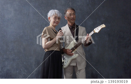 シニアのミュージシャン　男性のギタリストと女性のボーカル　黒背景 139193019