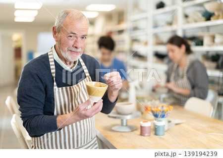 Mature potter demonstrates a clay cup he made with his own hands Mature potter demonstrates a clay cup he made with his own hands 139194239