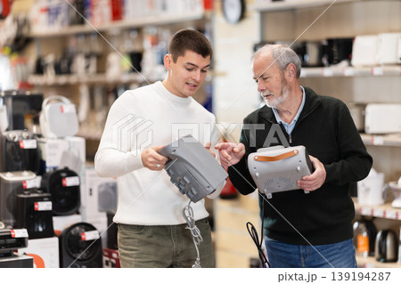 Two men choosing a household heater in an appliance store Two men choosing a household heater in an appliance store 139194287