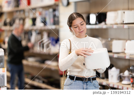 Positive young woman choosing toaster in hypermarket Positive young woman choosing toaster in hypermarket 139194312