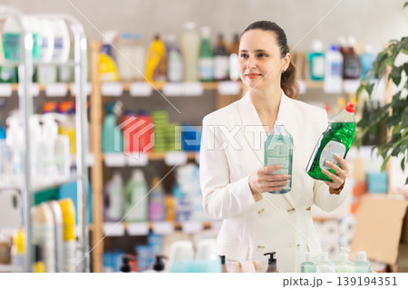 Adult woman chooses dishwashing detergent in store Adult woman chooses dishwashing detergent in store 139194351