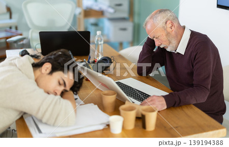 Wearied senior man and guy colleagues are dozing near workplace in office 139194388