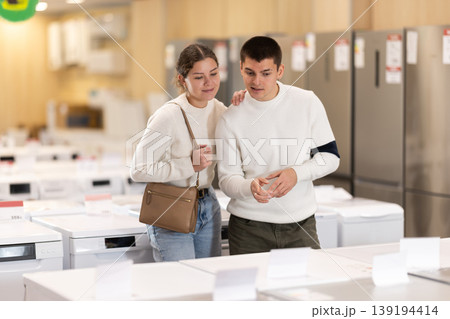 Couple customer inspect product range and selects dishwashing machine or washing machine Couple customer inspect product range and selects dishwashing machine or washing machine 139194414