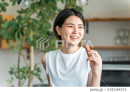 プロテインバー・栄養バーを食べるヨガウェア姿の若いアジア人女性 プロテインバー・栄養バーを食べるヨガウェア姿の若いアジア人女性 139194551