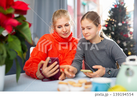 Woman and her daughter playing on smartphones 139194554