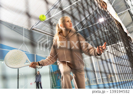 Sportive woman playing padel together with a partner. View through tennis net 139194582