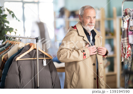 Elderly man trying on brown jacket in store Elderly man trying on brown jacket in store 139194590