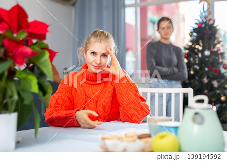 Mom sitting at table after quarreling with daughter during christmas time Mom sitting at table after quarreling with daughter during christmas time 139194592