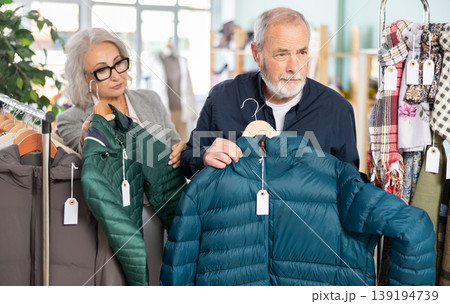 Family clothing store, senior couple customer chooses down jacket 139194739