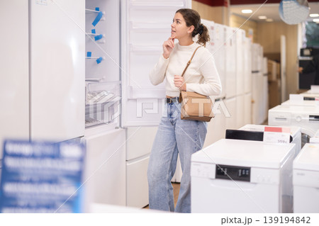 Young woman buyer examine fridge in detail before buying 139194842