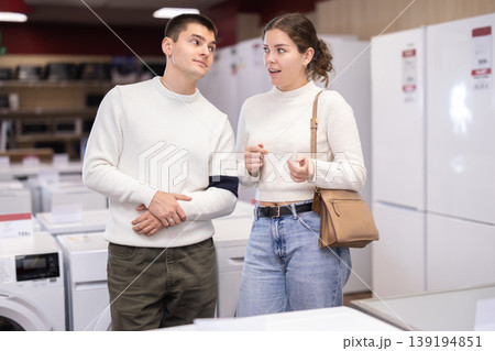 Young couple choosing washing machine or dishwasher Young couple choosing washing machine or dishwasher 139194851
