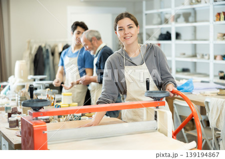 Girl in pottery workshop works with machine clay press roller Girl in pottery workshop works with machine clay press roller 139194867