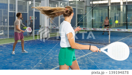 Teenage girl serving ball while playing padel in court 139194878