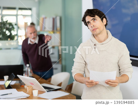 Elderly manager shows door to young employee who is holding resignation letter 139194885