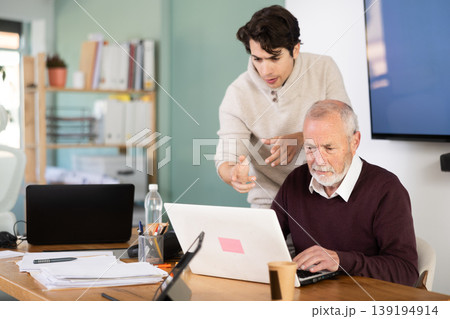 Guy helps elderly man complete task on laptop Guy helps elderly man complete task on laptop 139194914