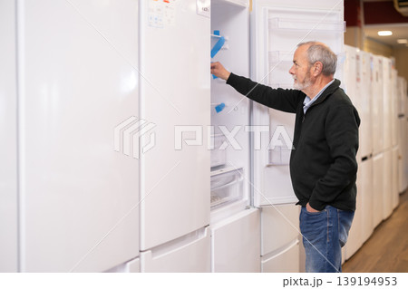 Elderly man chooses refrigerator in appliance store Elderly man chooses refrigerator in appliance store 139194953
