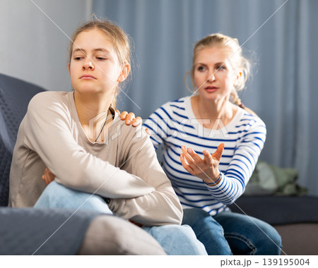 Sad female and daughter sitting at sofa and having quarrel Sad female and daughter sitting at sofa and having quarrel 139195004