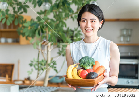 キッチンの前で野菜を持つスポーツウェア姿の若いアジア人女性（野菜不足・栄養バランス・緑黄色野菜） 139195032