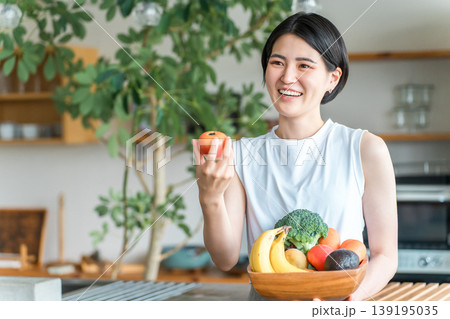 キッチンの前で野菜を持つスポーツウェア姿の若いアジア人女性（野菜不足・栄養バランス・緑黄色野菜） 139195035
