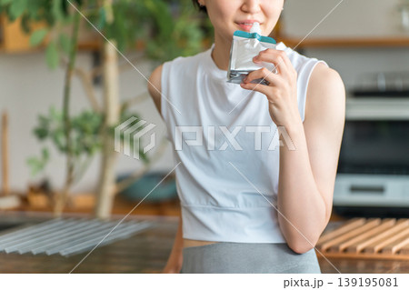 ゼリー飲料,栄養補助ゼリーで栄養補給するスポーツウェア姿の若いアジア人女性 139195081