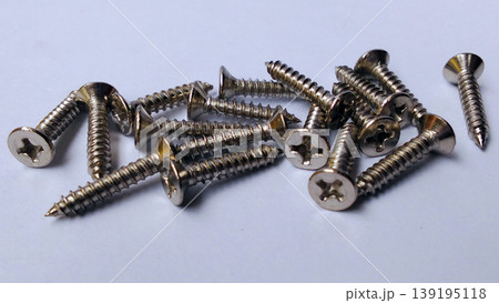 Shiny metal screws were scattered across the white surface. 139195118