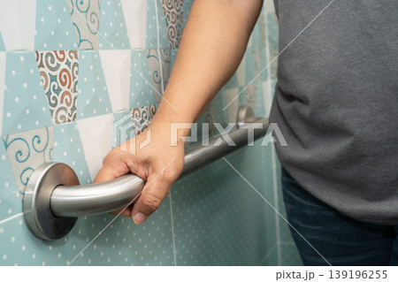 Asian woman patient use handrail safety in toilet support rail in bathroom. Asian woman patient use handrail safety in toilet support rail in bathroom. 139196255
