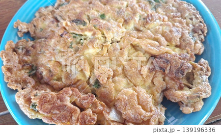 Golden brown and crispy Thai omelet seasoned with green onions, served as a traditional side dish in Thailand. 139196336